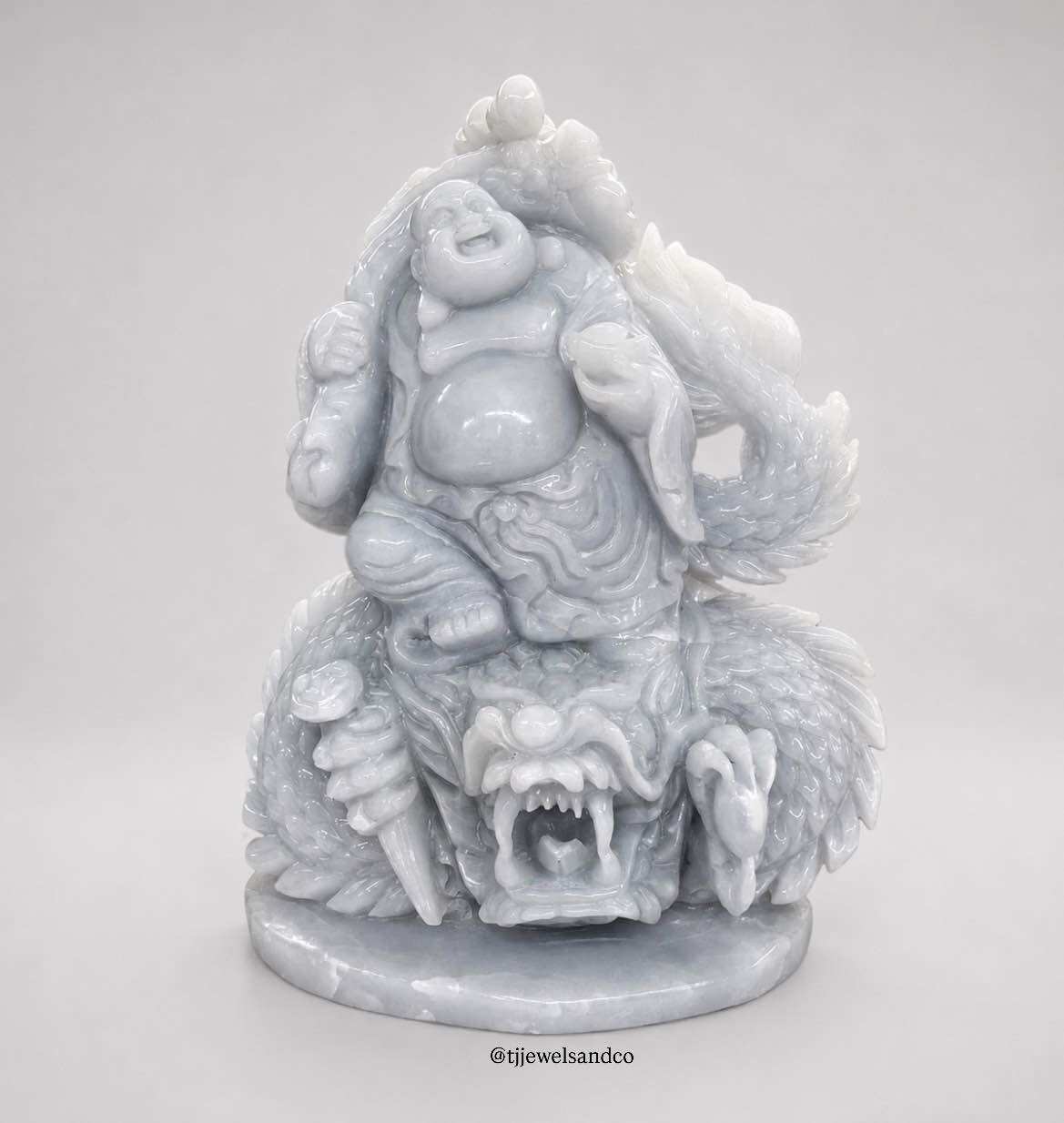 Budai with Prosperity Ingot and Longevity Peaches on Dragon |   Carved Statue of the Buddha Holding a Gold and Silver Bar, Stamped with a Dragon, Along with Auspicious Results, Burmese Purple Stone, Width 12.5 Inches, Height 15 Inches.